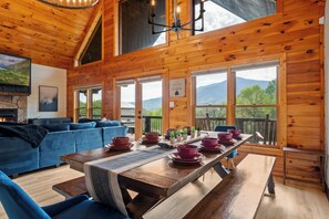 A wooden cabin with a dining table set for four, a blue sofa, and a fireplace.