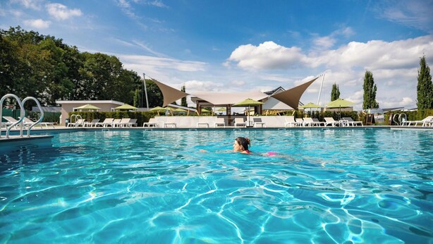 Ein Schwimmbecken mit klarem, blauem Wasser, Liegestühlen und Sonnenschirmen.