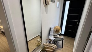 A modern hallway with a large mirror, a small table with a hat and a basket, and a door with a black handle. - Vacation apartment Happy Olive in Sevid near Trogir Croatia (Sevid na moru)