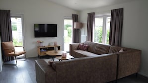 A living room with a sofa, armchair, coffee table, and a flat-screen TV. - Holiday Home in Bemelen Near Nature Reserve (Bemelen)
