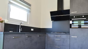 A modern kitchen with grey cabinets, a black range hood, and a built-in oven. - Holiday Home in Bemelen Near Nature Reserve (Bemelen)