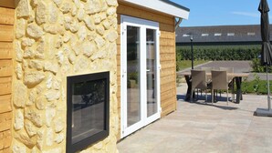 A stone exterior wall, a glass door, and a patio area with outdoor furniture. - Holiday Home in Bemelen Near Nature Reserve (Bemelen)