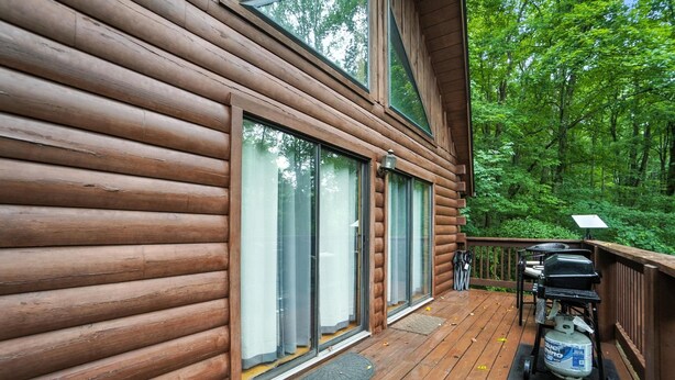 A log cabin with a deck, large windows, and a grill. - Slopeside | Hocking Hills Retreat, Covered Hot Tub (Laurelville)