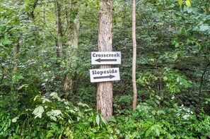 A directional signpost in a forested area with two arrows pointing left for Crosscreek and right for Slopeside.