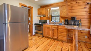 A kitchen with wooden cabinets, a stainless steel refrigerator, a stove, and a sink. - Slopeside | Hocking Hills Retreat, Covered Hot Tub (Laurelville)