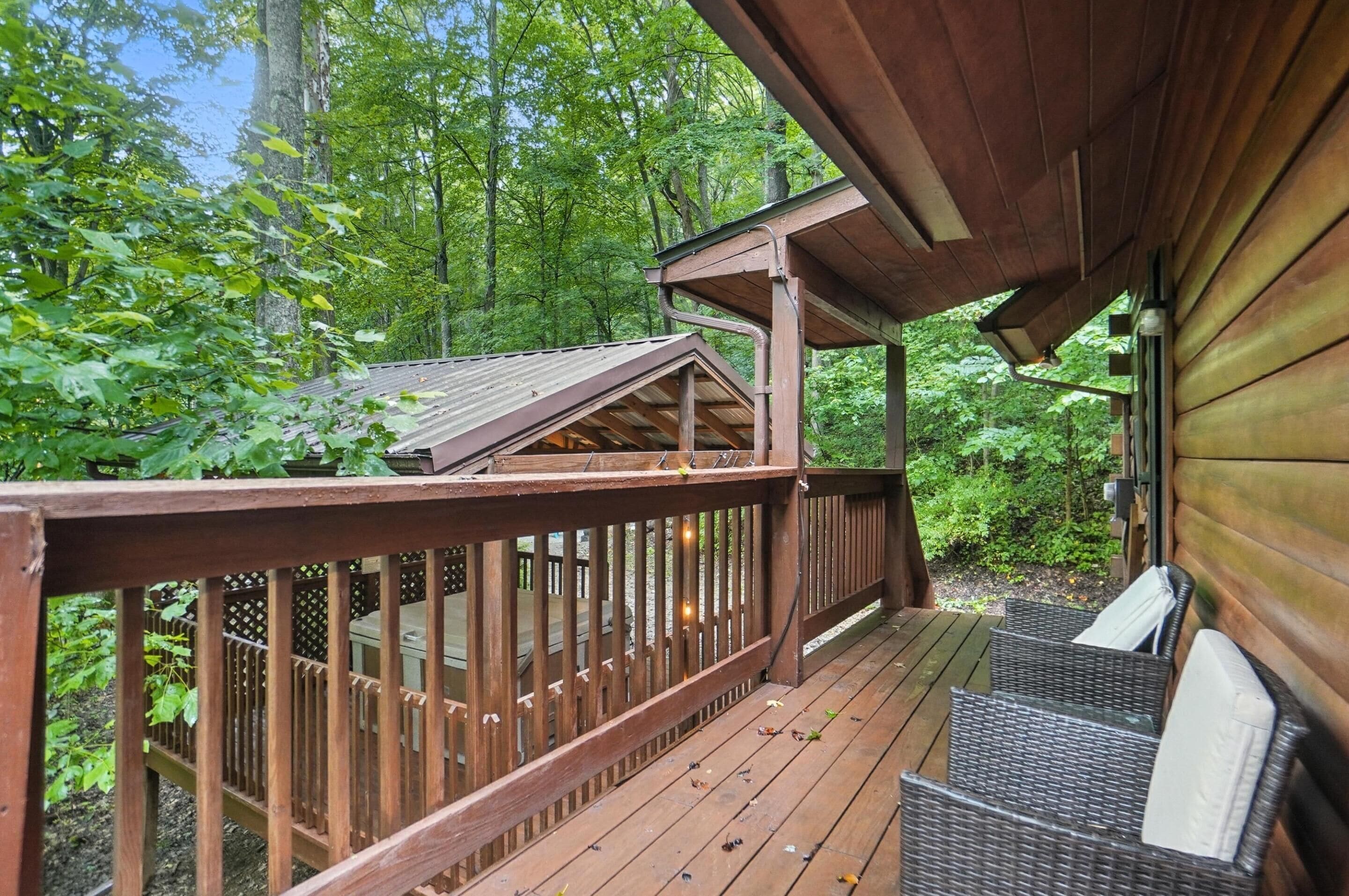 A wooden deck with wicker furniture, surrounded by dense forest.