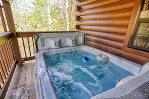 Un bain à remous sur une terrasse en bois, avec vue sur les arbres.