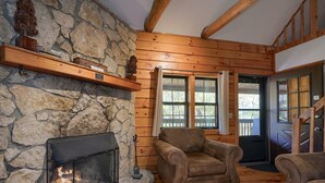 A cozy room with a stone fireplace, wooden beams, and a comfortable seating area. - Crosscreek | Hocking Hills, 6 Acres, Hot Tub, Pets (Laurelville)