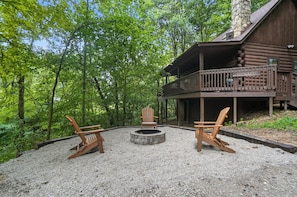 Une cabane dotée d’une terrasse et d’un foyer extérieur, le tout entouré de fauteuils Adirondack.
