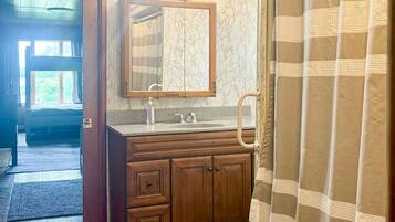 Une salle de bain avec un meuble-lavabo en bois, un miroir, un lavabo et un rideau de douche.
