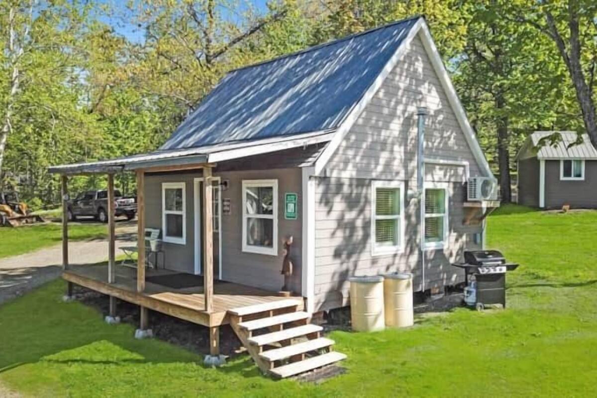 A small, single-story cabin with a porch and a covered outdoor seating area.