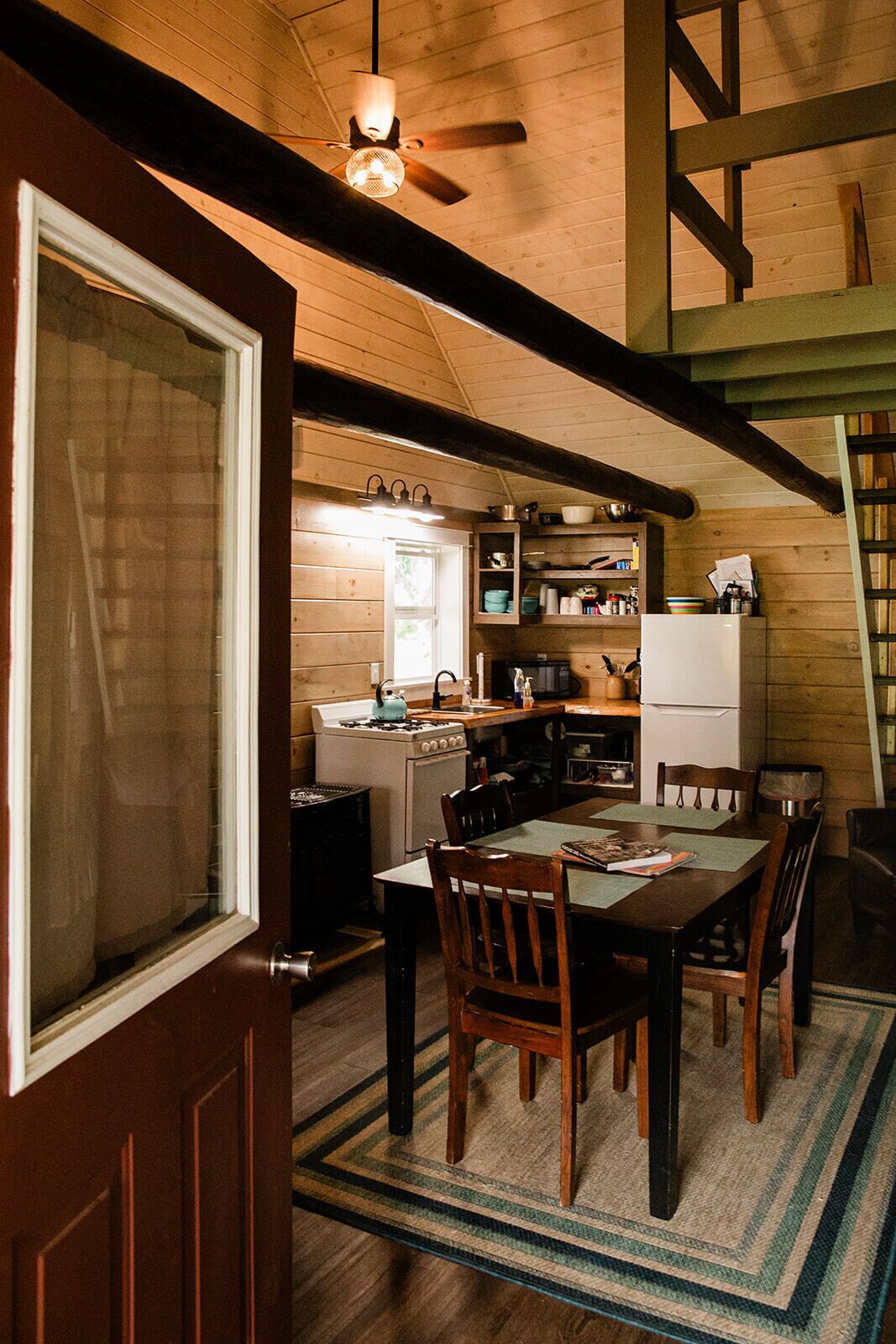A rustic kitchen with wooden beams, a stove, and a refrigerator.