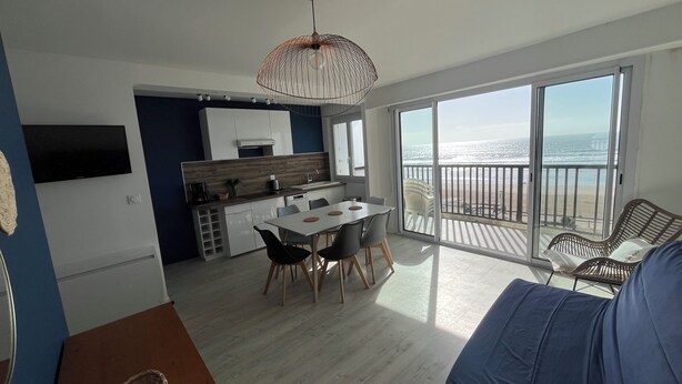 En modern lägenhet med kök, matplats och en balkong med utsikt över havet.