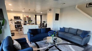 A modern living room with a blue sofa, grey sofa, and a coffee table with a vase of flowers. - Rodeo-Ready Retreat! Newly Renovated & Stylishly Relaxing (Houston)