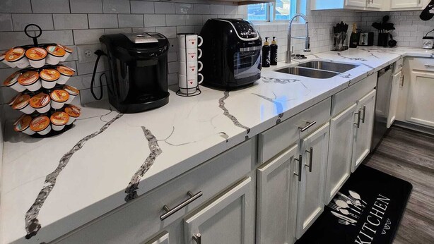 A modern kitchen with white cabinets, a marble countertop, a coffee maker, and a coffee station. - Rodeo-Ready Retreat! Newly Renovated & Stylishly Relaxing (Houston)