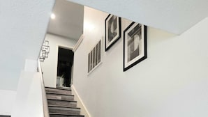 A staircase with wooden steps and a white wall with three framed pictures. - Rodeo-Ready Retreat! Newly Renovated & Stylishly Relaxing (Houston)