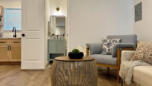 A modern living room with a round wicker coffee table, a grey sofa with patterned cushions, and a wooden floor. - Charming 4-bedroom house with WiFi and AC in enchanting Houston (Houston)
