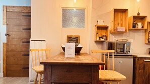 A cozy kitchen with wooden furniture, a dining table, chairs, a microwave, and a refrigerator. - La Chaumière - BedinShop - historic center - France (Romans-sur-Isère)