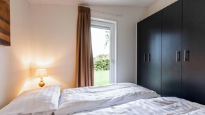 Une chambre avec deux lits, une fenêtre avec des rideaux, une lampe et une armoire.
