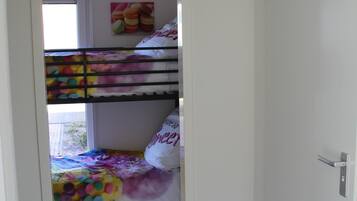 Una cama litera con ropa de cama de colores y una almohada con el texto 'SWEET'.