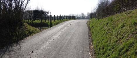 A rural road with a fence on one side and a grassy hill on the other.