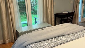 Un dormitorio con cama, una ventana con cortinas, una mesita y una silla.