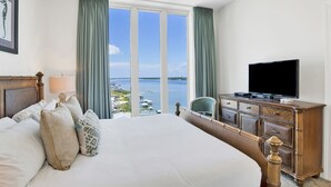 Camera d'albergo con un ampio letto, televisione, una cassettiera in legno e vista mare.