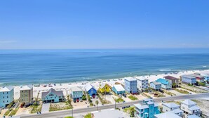 Una zona residenziale sulla costa con accesso alla spiaggia, caratterizzata da case colorate e una strada che conduce al mare.