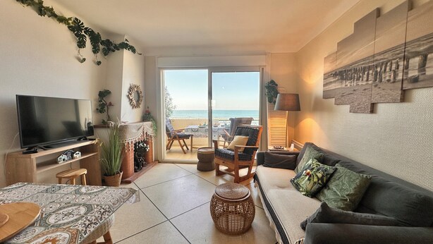 Sala de estar con televisor, chimenea, sofá y vista a la playa.