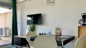 A modern dining area with a flat-screen TV, a table with chairs, a coffee maker, and a sign that reads 'CUISINE.'