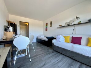 A modern living room with a sofa, chairs, a coffee machine, and a dining table.
