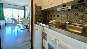 A compact kitchen with a sink, white cabinets, and a patterned backsplash.