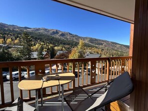 A balcony with a wooden railing, two tables, and a cushioned chair. - 100m from ski slopes, 2nd floor, balcony, tv, 29m², Méribel (Méribel - Les Allues)