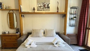Een keurig opgemaakt slaapkamer met een bed, nachtkastjes, een dressoir en een spiegel.