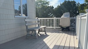 A wooden deck with a white railing, a covered grill, and a bench. -  Newly Renovated 3-Bedroom House in Surf City - Pet Friendly (Surf City)