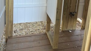 A wooden deck with a white door, a metal ladder, and visible plumbing pipes. -  Newly Renovated 3-Bedroom House in Surf City - Pet Friendly (Surf City)