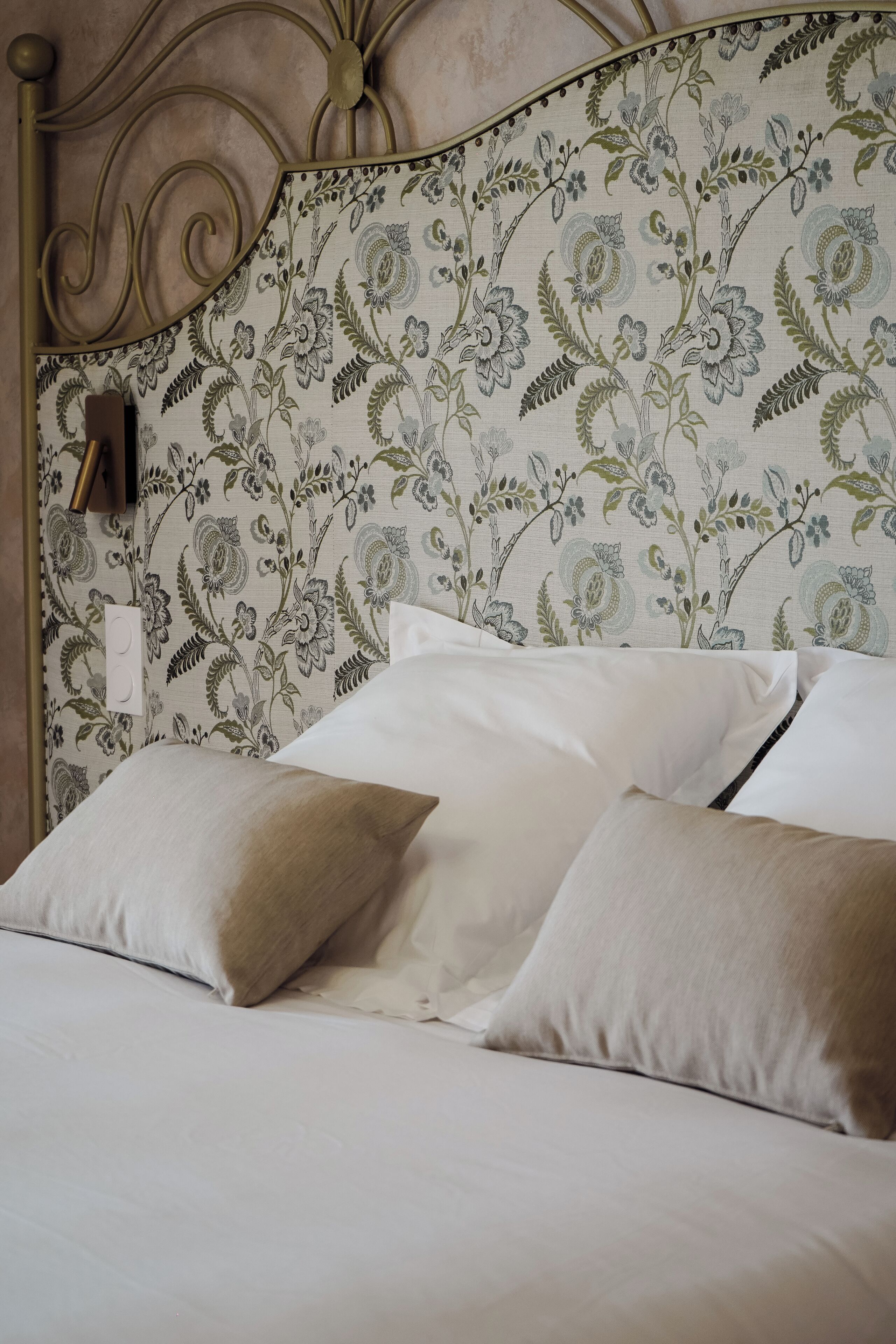 Ein Bett mit einem blumengemusterten Kopfteil und weißer Bettwäsche.