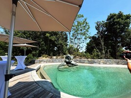 Piscina clara com parede de pedra e deck de madeira.