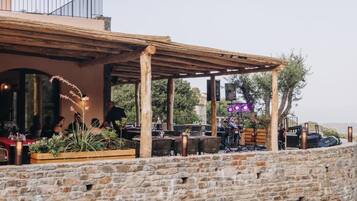 Un patio al aire libre con paredes de piedra, pérgola de madera y mobiliario exterior.