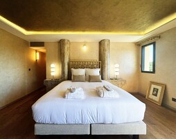 Uma cama grande com cabeceira, duas mesas de cabeceira e um quadro na parede.