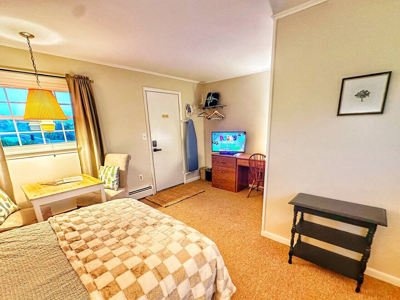 Une chambre d’hôtel comprenant un lit, un bureau, une chaise, une télévision et une petite table.