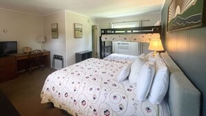 A hotel room with a bed, a desk, a chair, a TV, and a lamp. - Room 7 - family room sleeps 4 (Manchester)