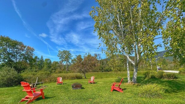 A grassy outdoor area with red Adirondack chairs and a fire pit. - Room 7 - family room sleeps 4 (Manchester)