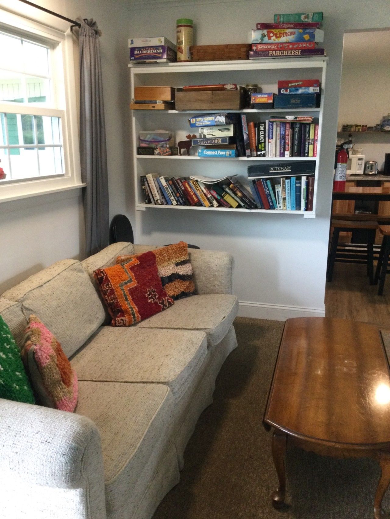 Un salon comprenant un canapé, une table basse et une bibliothèque remplie de livres et de jeux de société.