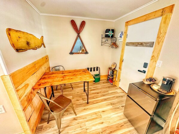 Une cuisine de taille réduite, avec une table en bois, des chaises, un réfrigérateur et un élément de décoration murale original.