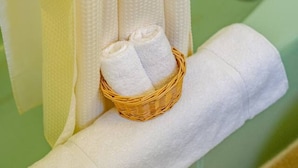 A bathroom with a green bathtub, a white towel, and a wicker basket containing two rolled white towels. - Alpine 5, cozy Vermont retreat (Manchester)