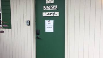 A green door with 'The Snack Lounge' signage and a business card.