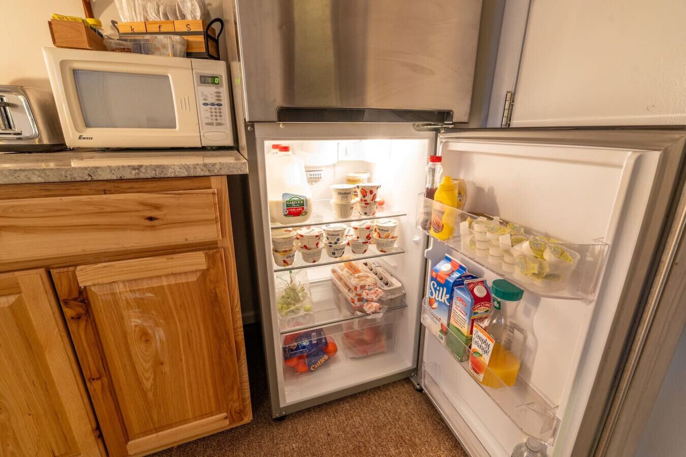 A compact kitchen with a microwave, a refrigerator, and wooden cabinets.