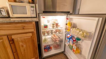 A compact kitchen with a microwave, a refrigerator, and wooden cabinets.