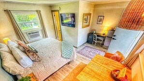 A bedroom with a bed, bedside table, and a TV mounted on the wall.